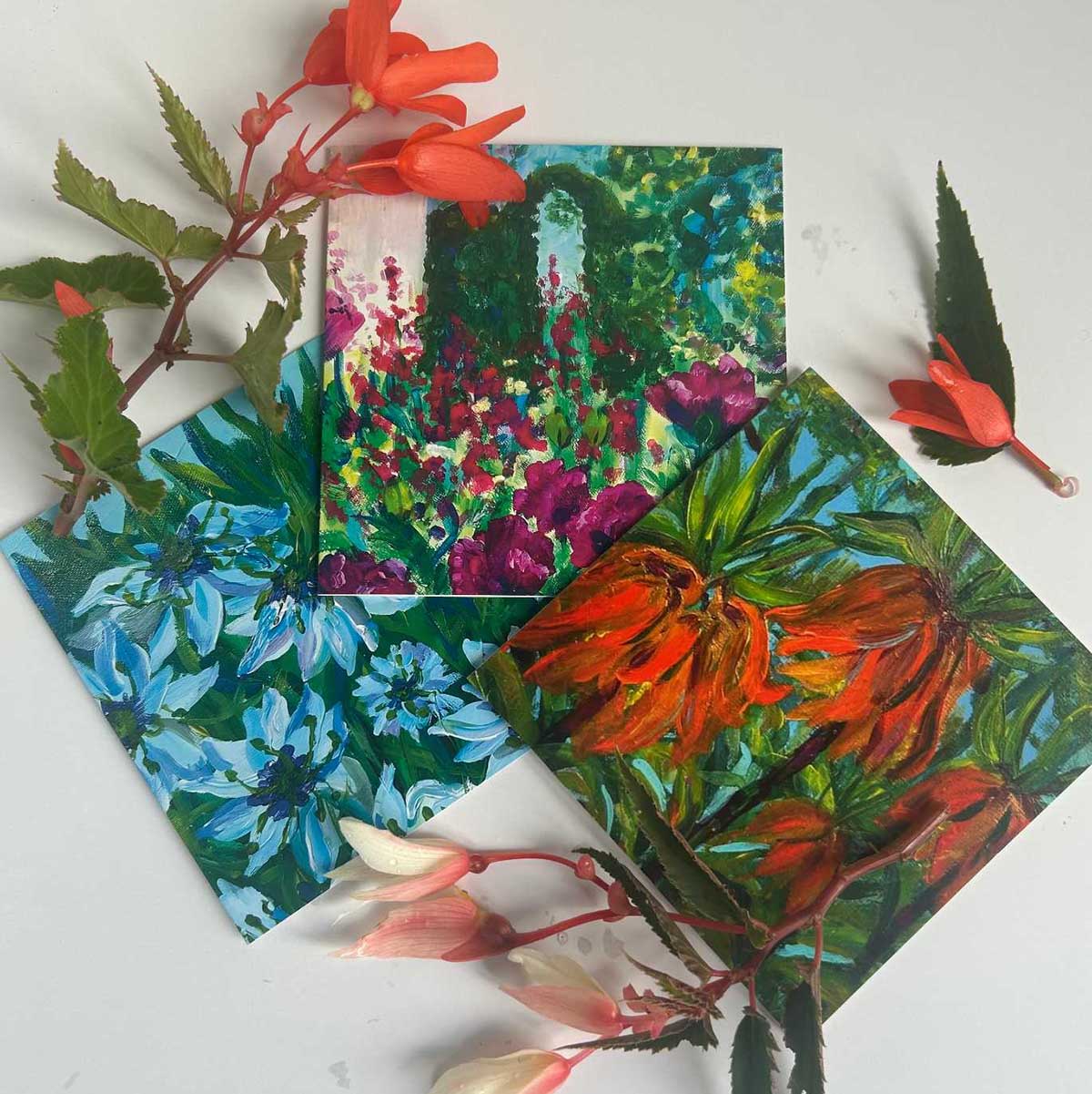 Three colourful cards depicting flowers in reds, pinks and blues, surrounded by several colourful flower stems on a white background.